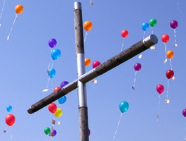 Ein Kreuz, über dem bunte Luftballons fliegen.